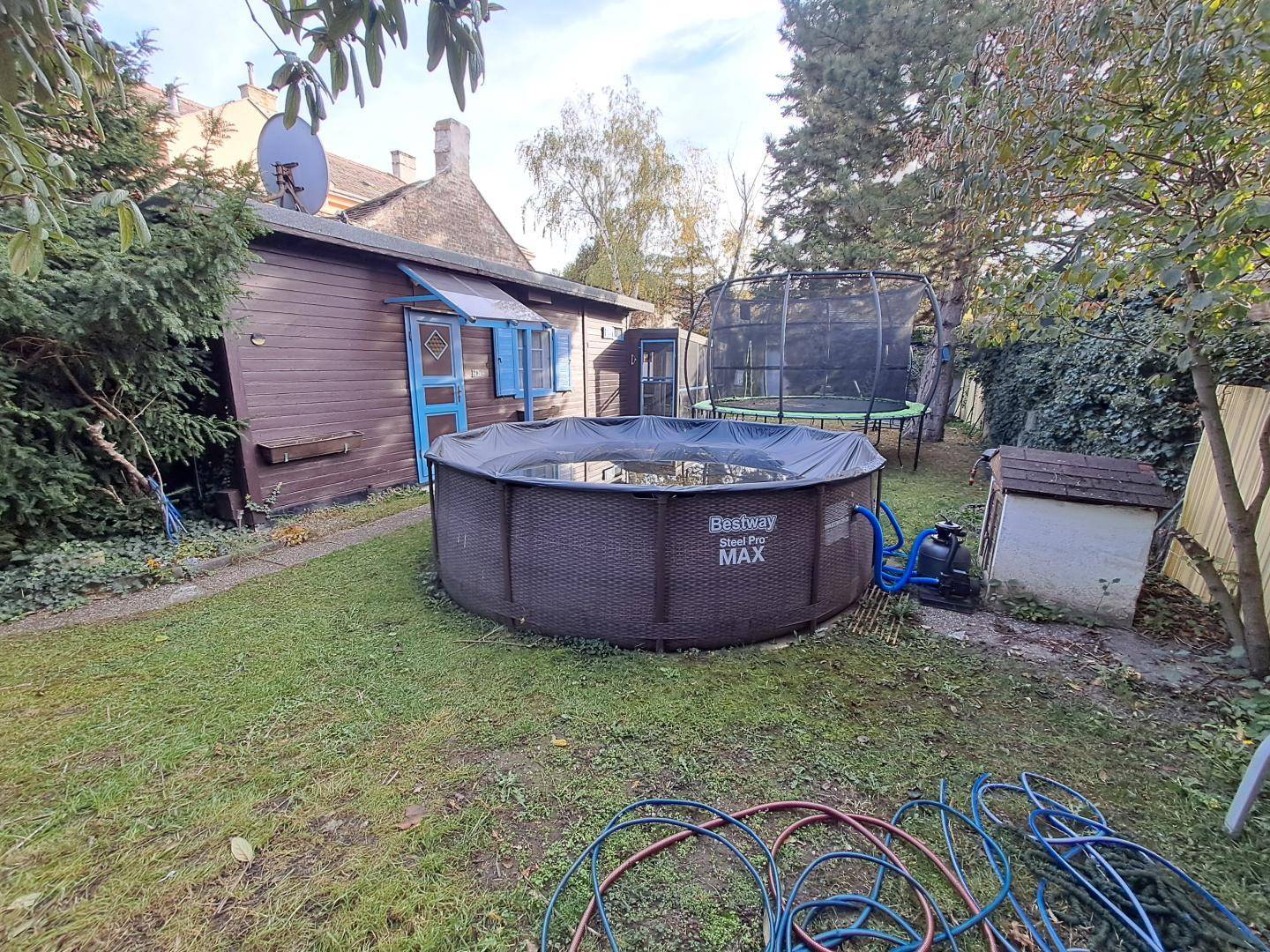 Gartenbereich mit großem Aufstellpool, Trampolin und einem kleinen Holzschuppen im Hintergrund.