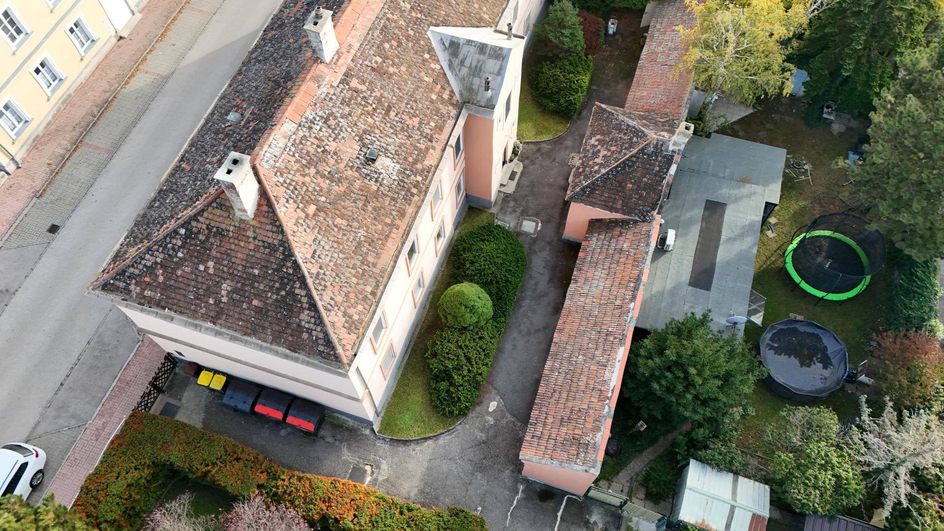 Draufsicht auf das Anwesen mit Hauptgebäude, Nebengebäude, Zufahrt und Gartenbereich mit Pool und Trampolin.