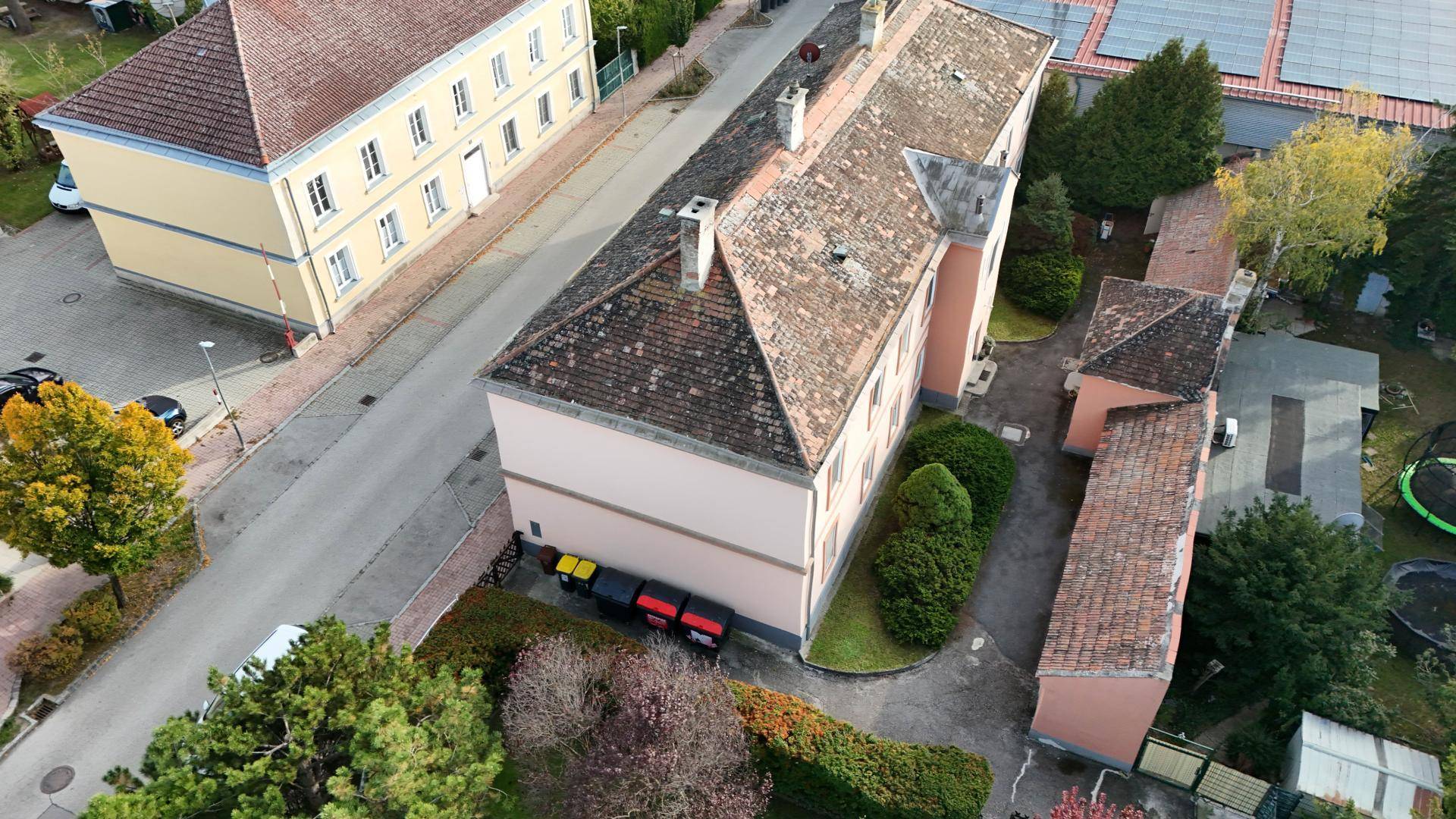 Luftaufnahme des Anwesens mit Hauptgebäude, Nebengebäude, Zufahrt und Gartenbereich mit Pool und Trampolin.