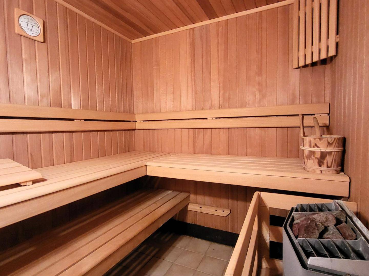 Holzvertäfelte Sauna mit bequemen Bänken und einem traditionellen Saunaofen.