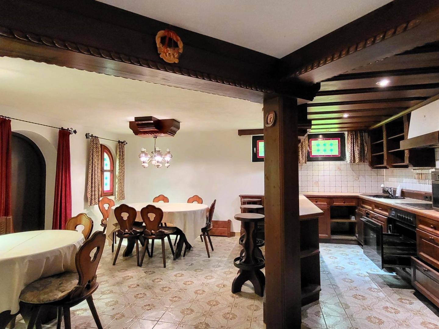 Rustikaler Wohn- und Essbereich mit Holzbalken, traditionellen Möbeln und integrierter Küche.