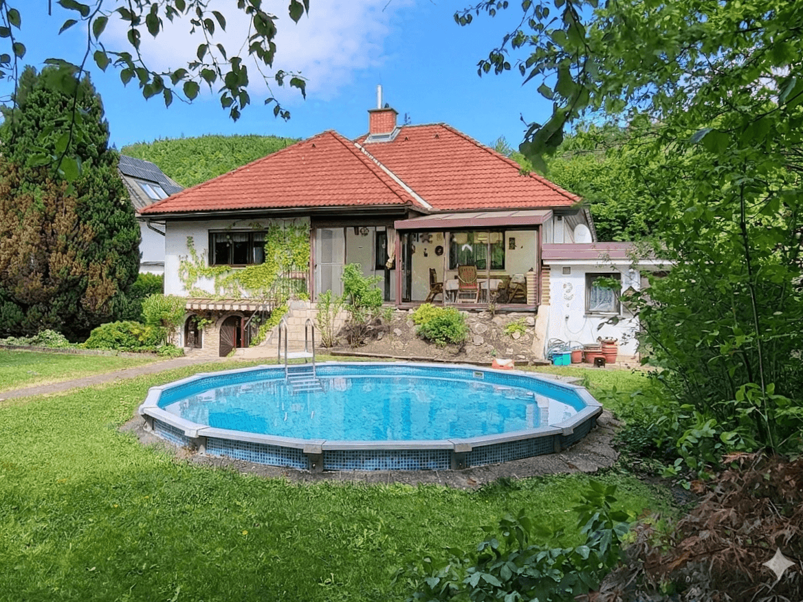 Idyllisches Einfamilienhaus mit großem Garten und einem runden Aufstellpool im Grünen.