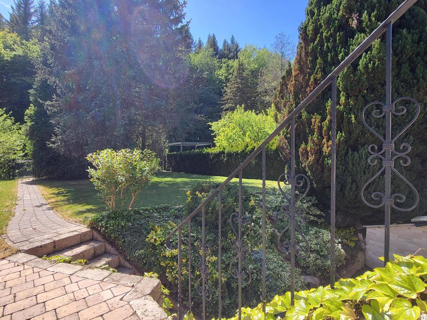 Steintreppe führt durch üppige Bepflanzung zu einem weiteren Gartenbereich.