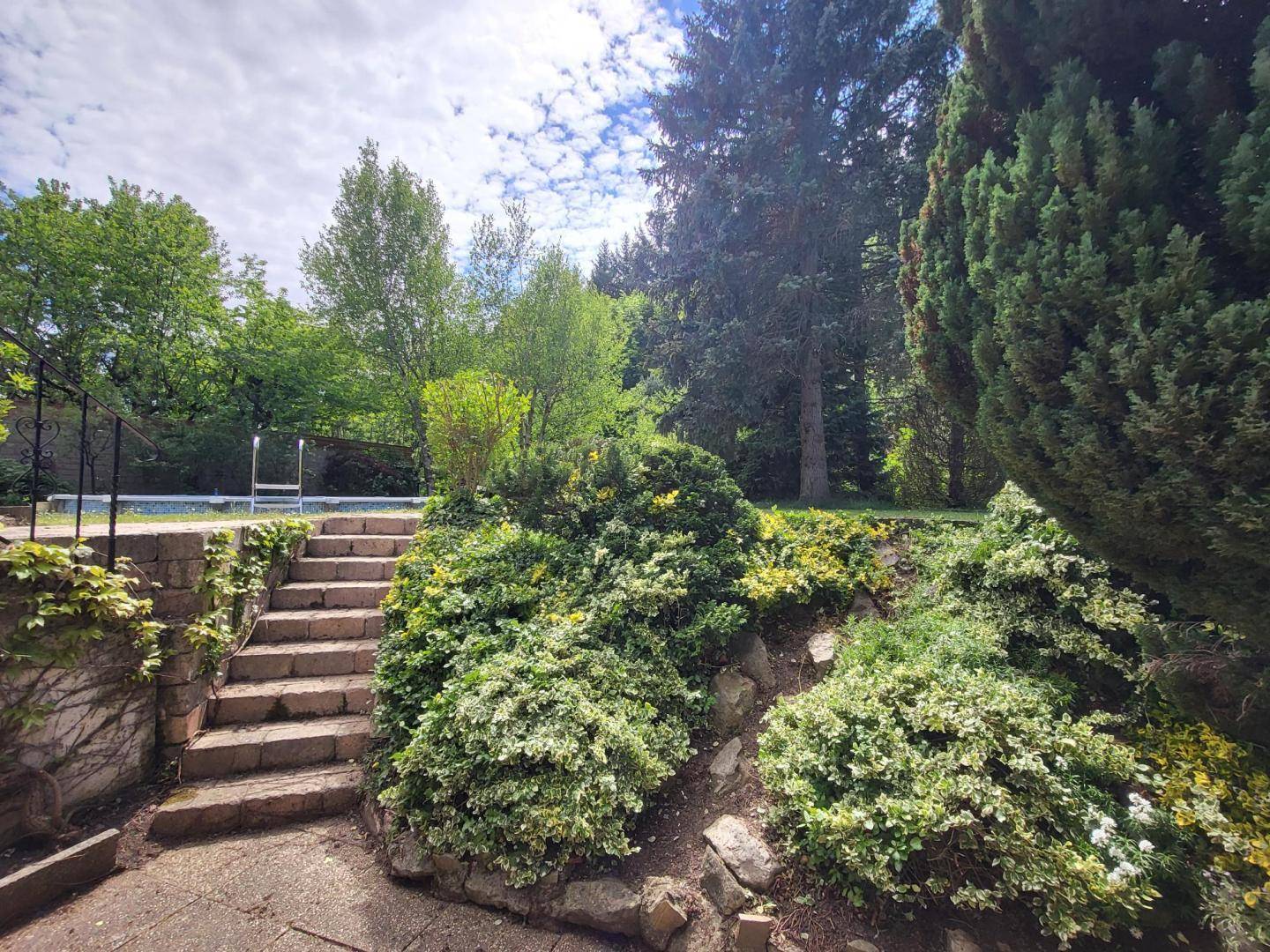 Steintreppe umgeben von vielfältiger Bepflanzung führt zu den oberen Gartenbereichen.