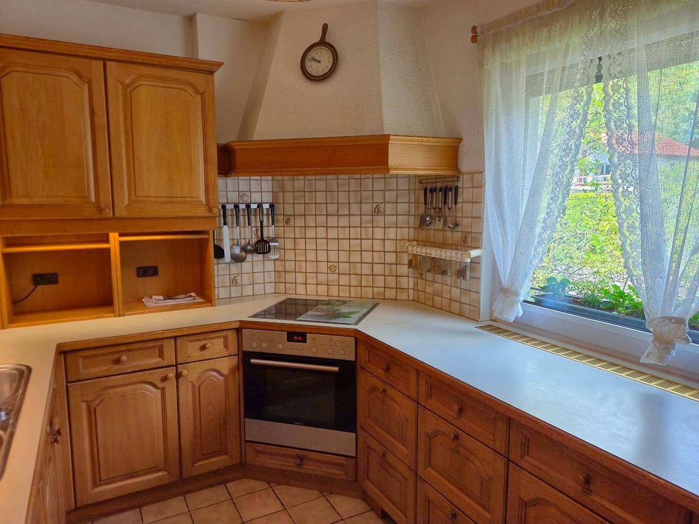 Traditionelle Holzküche mit Fliesenrückwand, Einbaugeräten und Fenster mit Gartenblick.