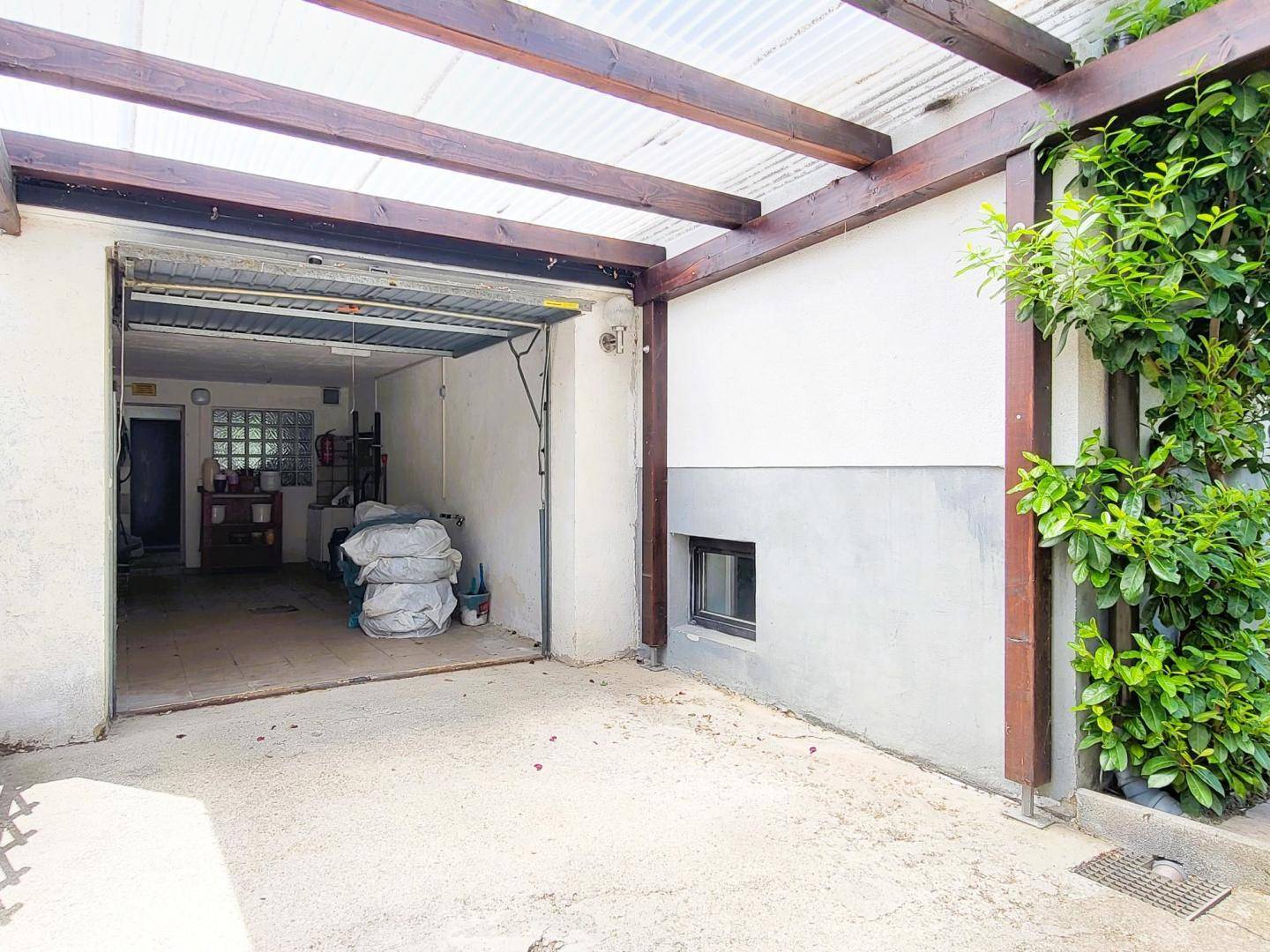 Innenansicht der Garage mit Stauraum und Blick auf den überdachten Carport-Bereich.
