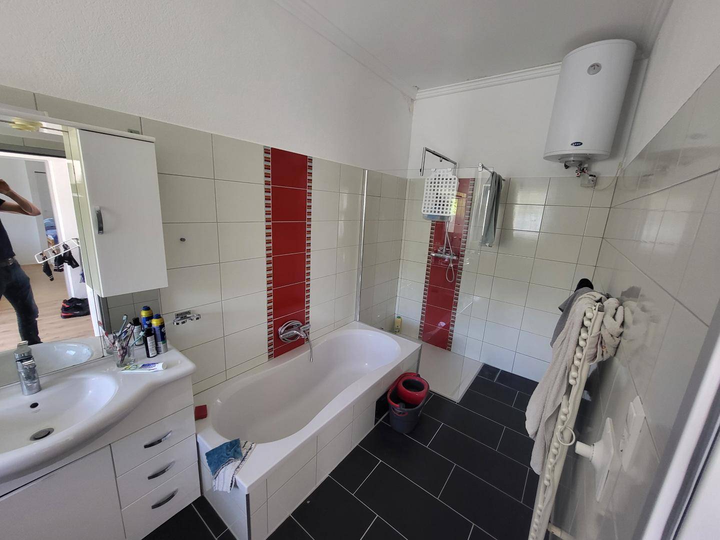 Modernes Badezimmer mit Badewanne, Dusche und schwarzen Bodenfliesen.