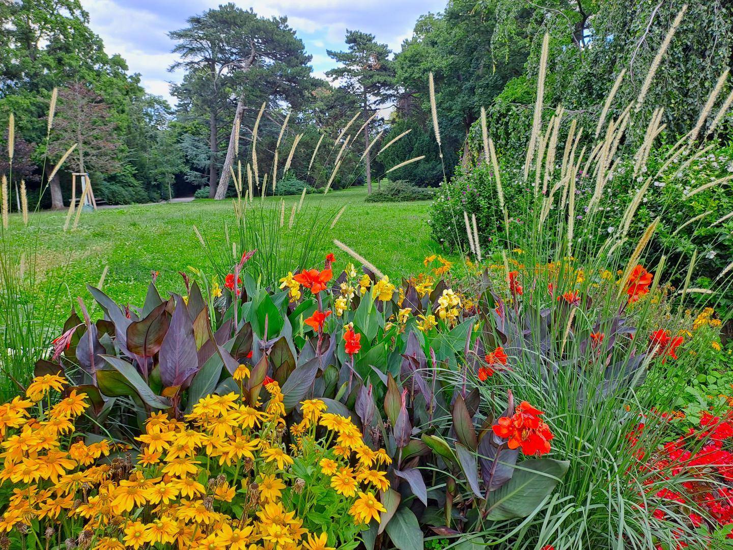 Farbenprächtiges Blumenbeet in einer gepflegten Gartenanlage mit üppiger Vegetation.