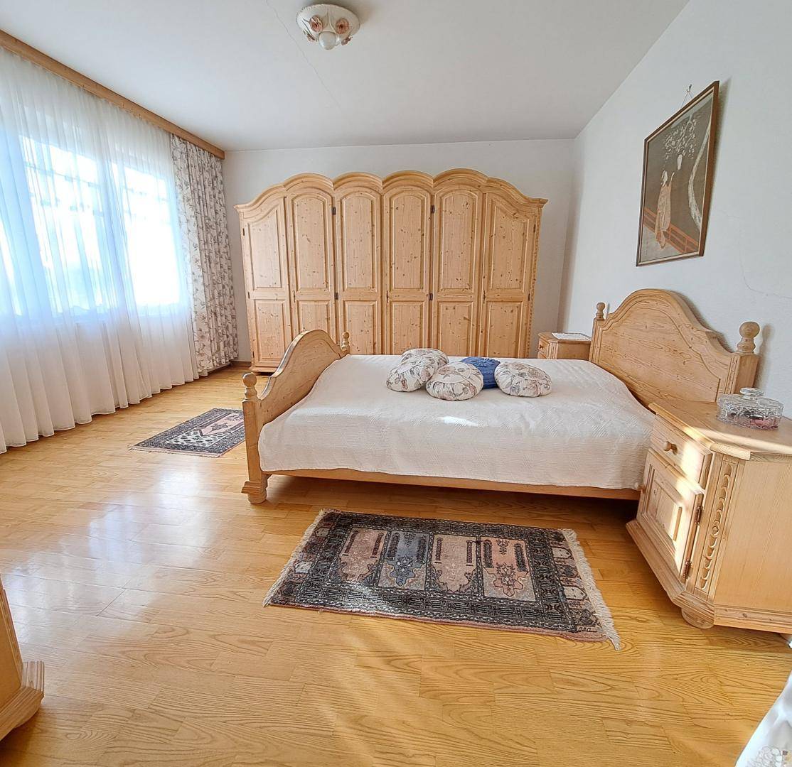 Geräumiges Schlafzimmer mit hellen Holzmöbeln, Parkettboden und großen Fenstern.