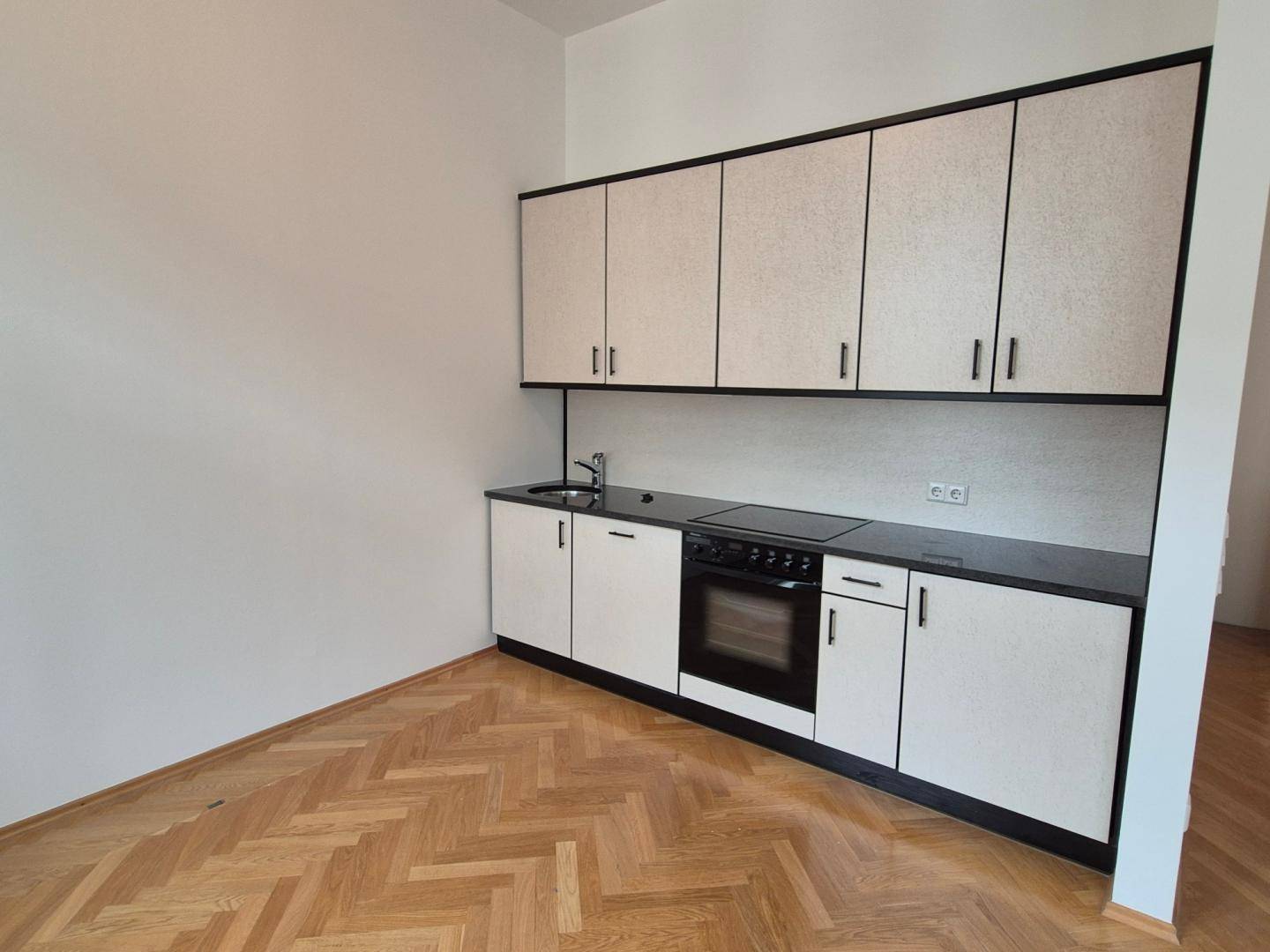 Funktionale Küchenzeile mit weißen Schränken, integriertem Backofen und Kochfeld.