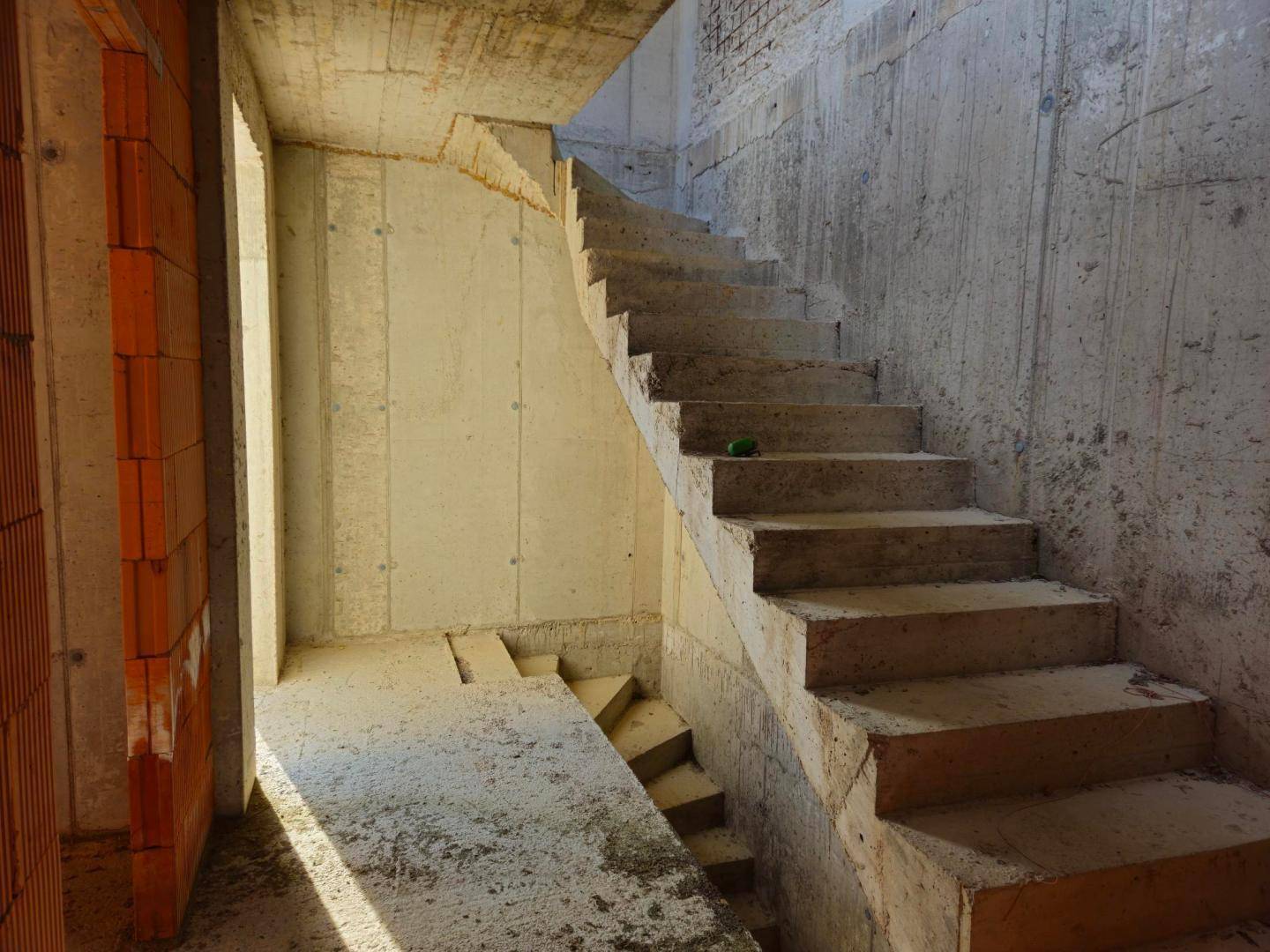 Betonierte Treppe im Rohbau, die verschiedene Ebenen des Gebäudes miteinander verbindet.