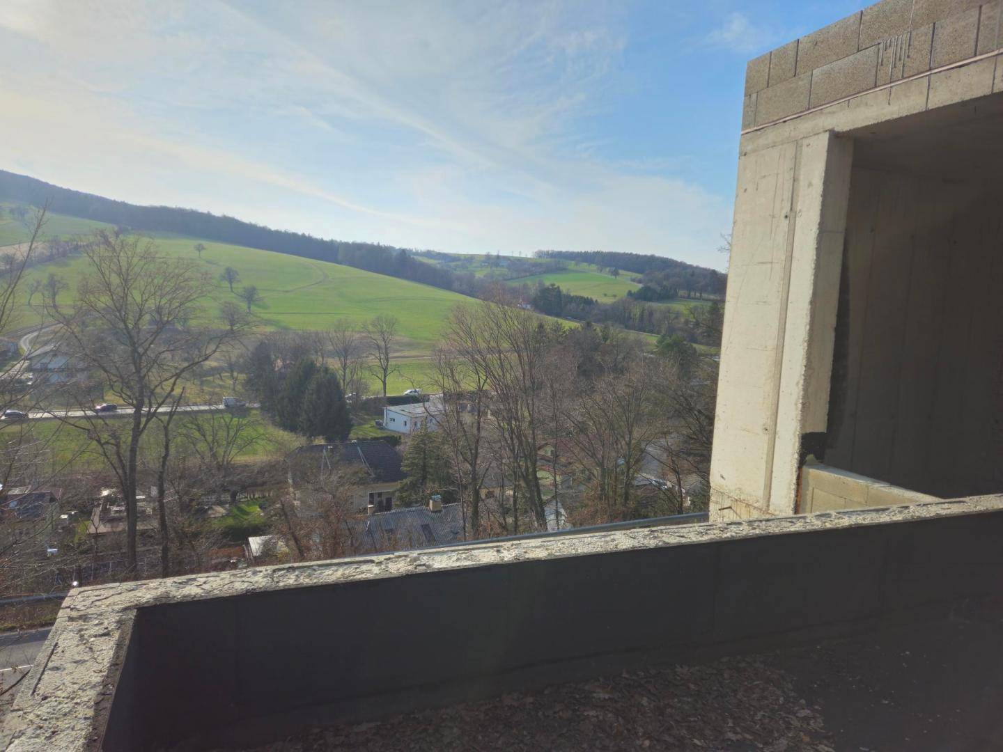 Panoramablick von einer oberen Ebene des Rohbaus auf die weite grüne Hügellandschaft.