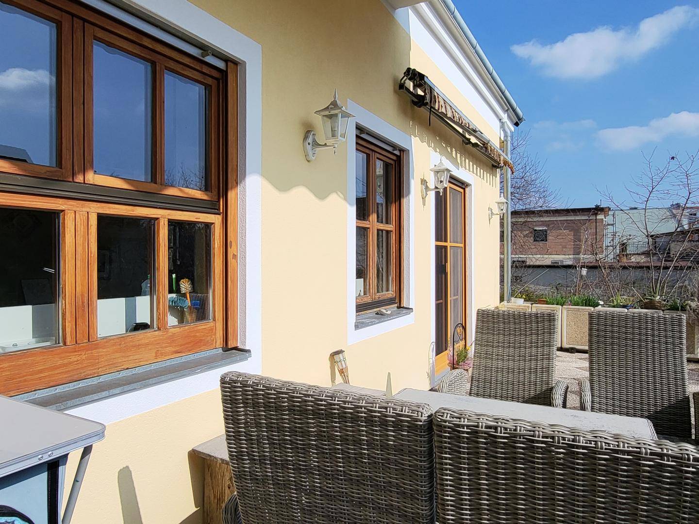 Gemütlicher Außenbereich mit Korbmöbeln auf einer Terrasse neben dem Haus.