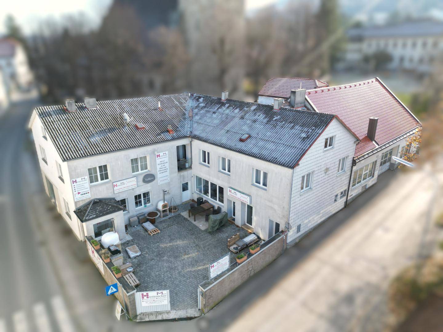 Überblick über einen Gebäudekomplex mit gepflastertem Hof und verschiedenen Dachformen.