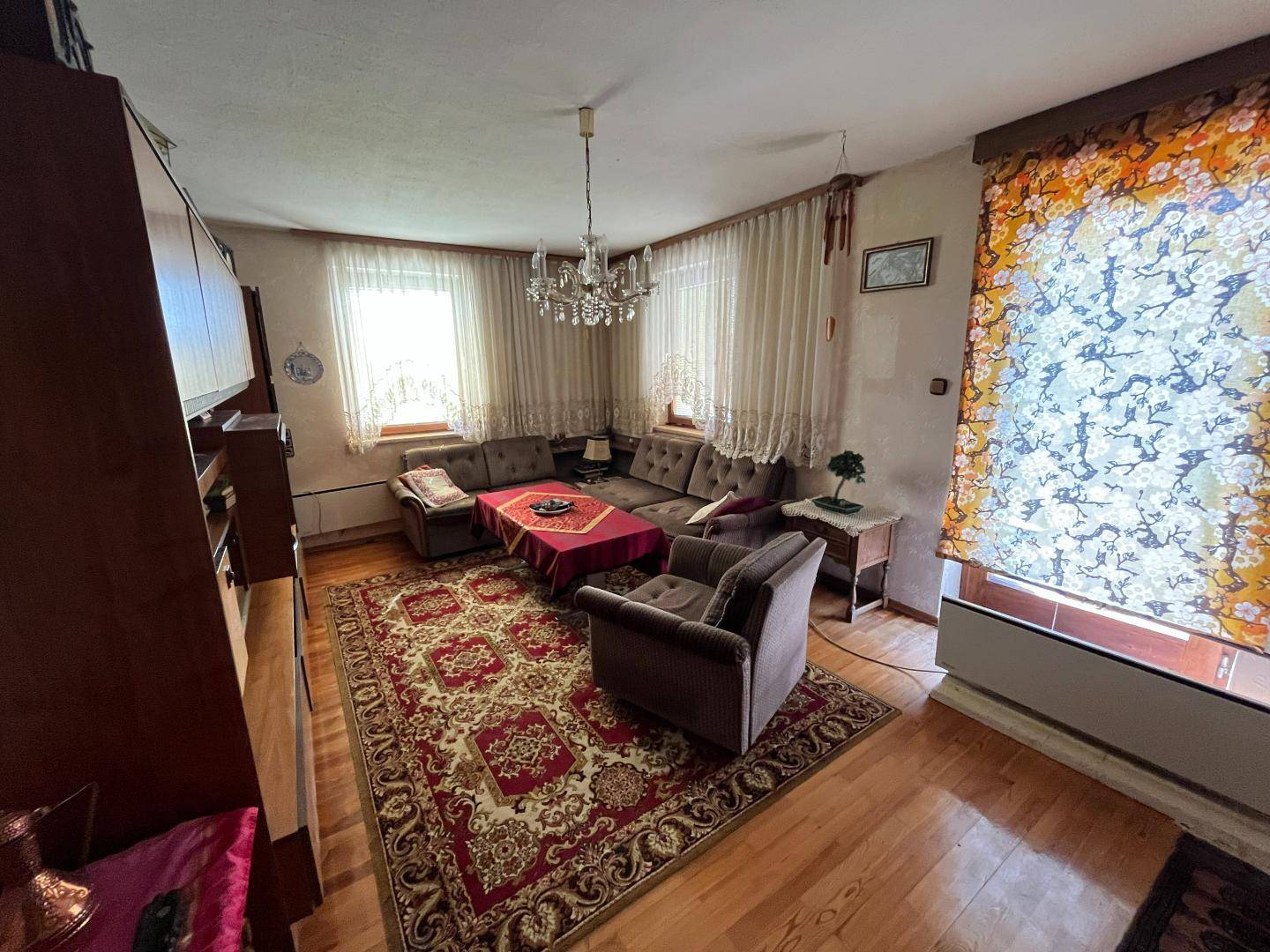 Gemütliches Wohnzimmer mit Holzboden, großem Teppich und bequemen Sofas.