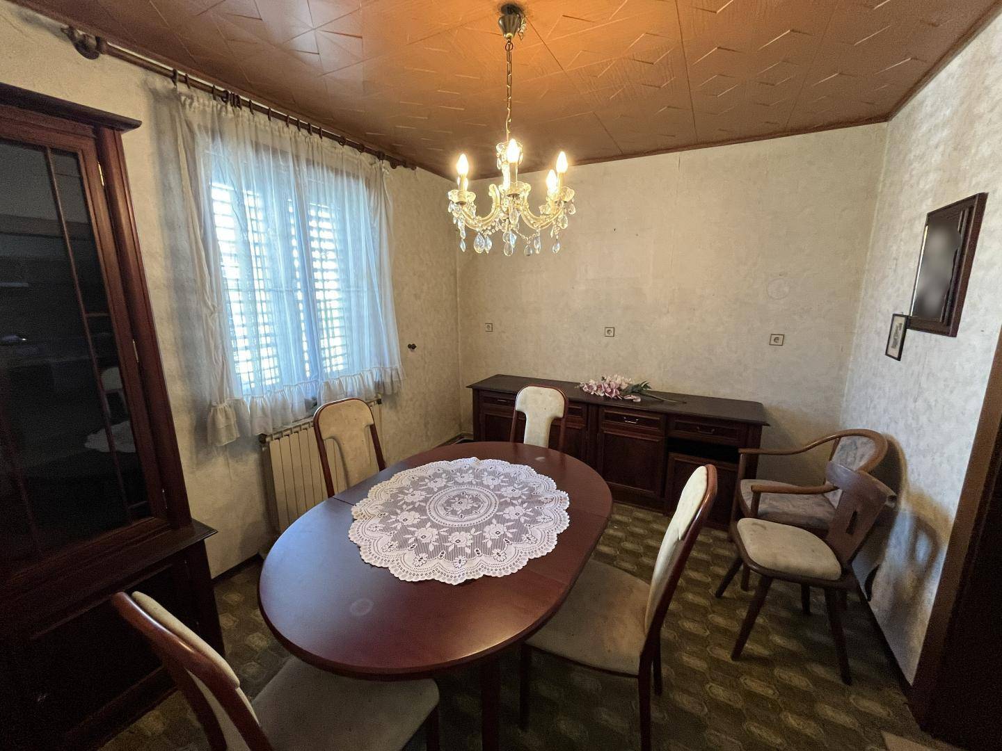 Klassisches Esszimmer mit ovalem Holztisch, Kronleuchter und gemusterter Decke.