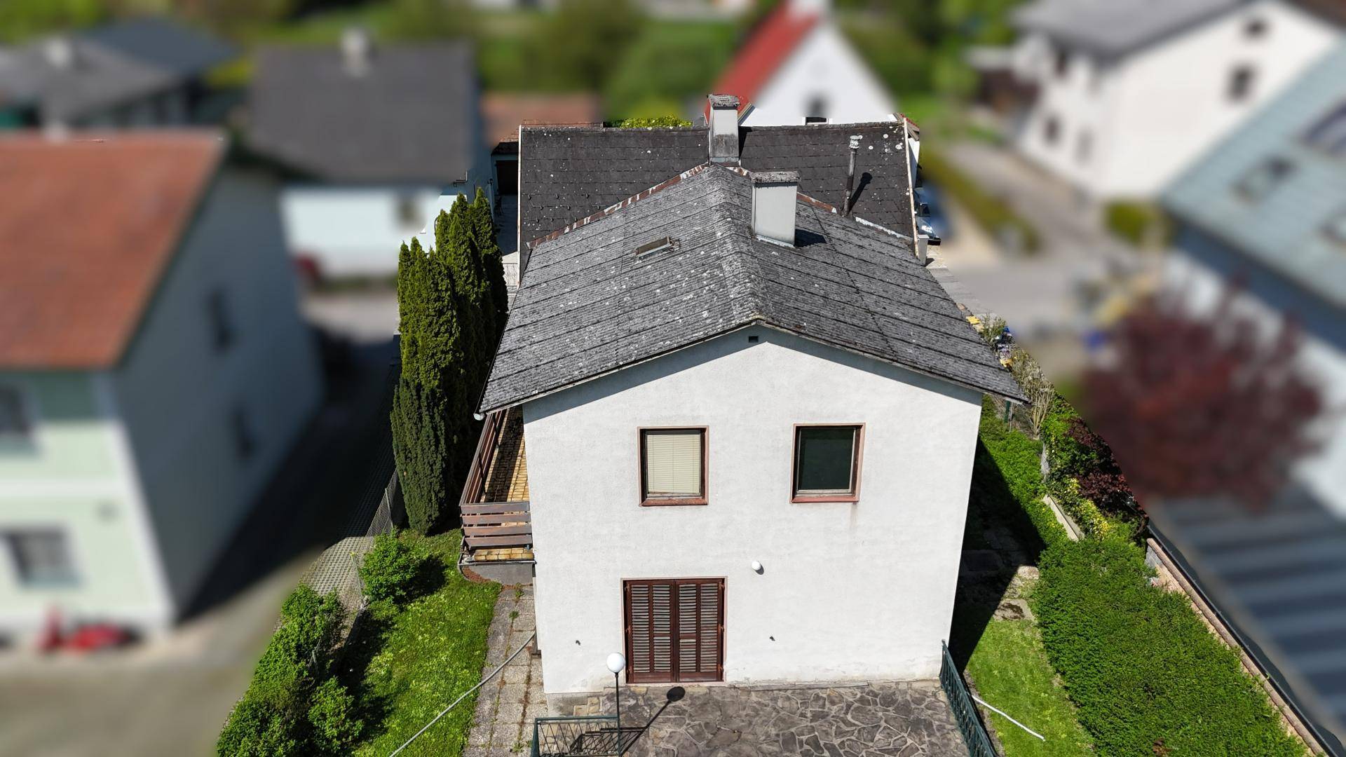 Luftaufnahme eines Einfamilienhauses mit Satteldach und Garten in einer Wohnsiedlung.