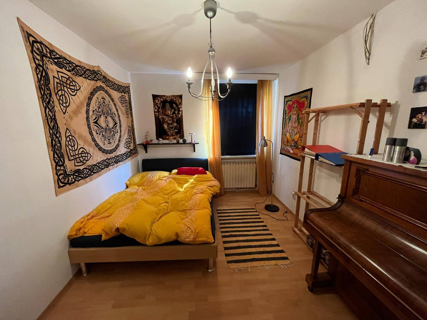 Helles Schlafzimmer mit Holzboden, Einzelbett und dekorativen Wandteppichen.