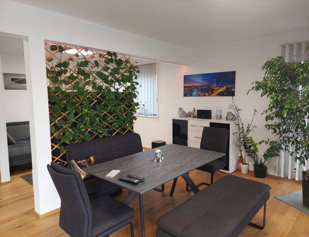 Essbereich mit modernem Tisch, Sitzbänken und einer dekorativen grünen Pflanzenwand.