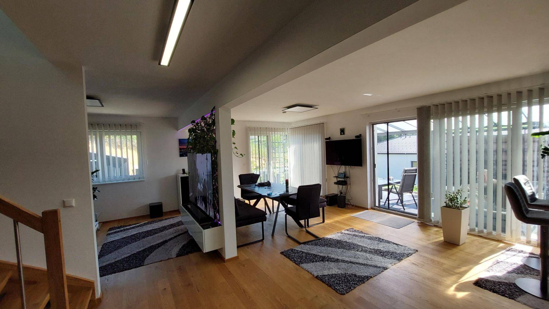 Heller offener Wohn-Essbereich mit Holzboden, Esstisch und Zugang zur Terrasse.