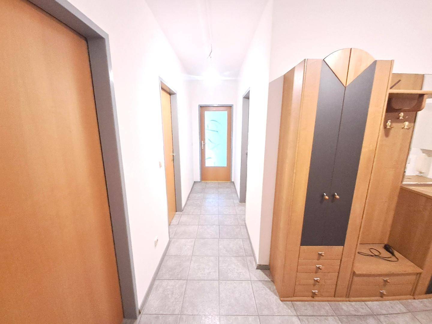 Heller Flur mit Fliesenboden und einem praktischen Garderobenschrank.