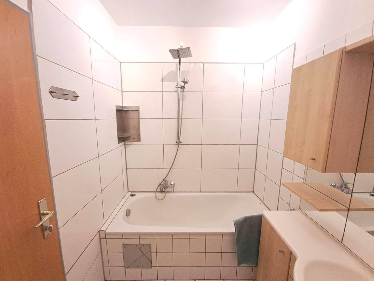 Badezimmer mit Badewanne, Duschfunktion und weißen Wandfliesen.