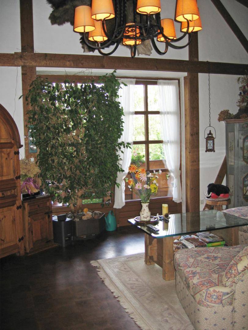 Helles Wohnzimmer mit großem Fenster, Holzbalken und traditioneller, detailreicher Dekoration.