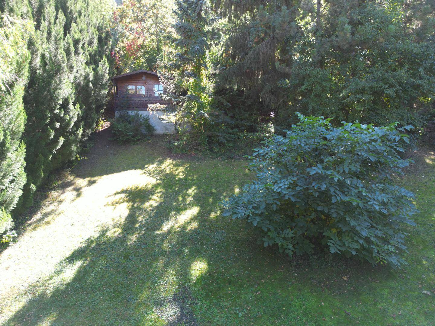 Gepflegter Gartenbereich mit Rasenfläche und einem kleinen Holzgartenhaus im Hintergrund.