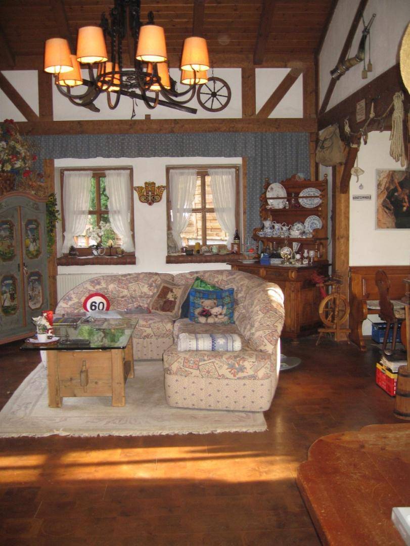 Gemütliches Wohnzimmer im Landhausstil mit Holzbalken und traditioneller, farbenfroher Einrichtung.