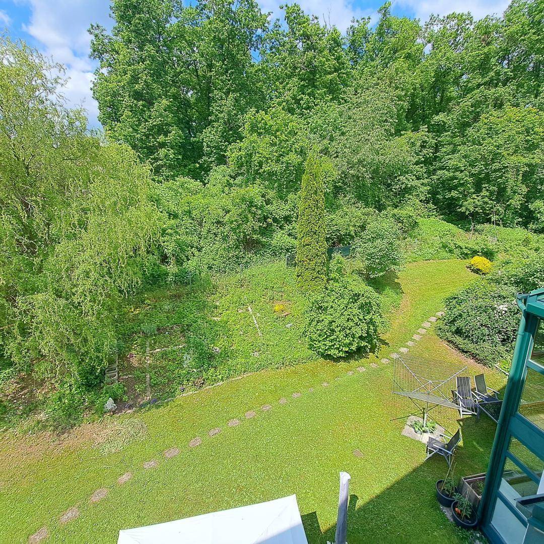 Großer, gepflegter Garten mit Rasenflächen, Bäumen und einer kleinen Terrasse mit Sitzgelegenheiten.