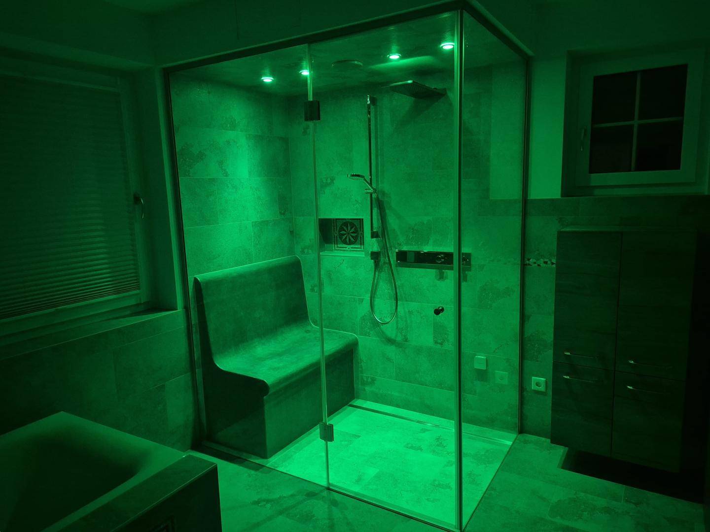 Wellness-Badezimmer mit Dampfdusche und farbiger Beleuchtung für entspannende Momente.