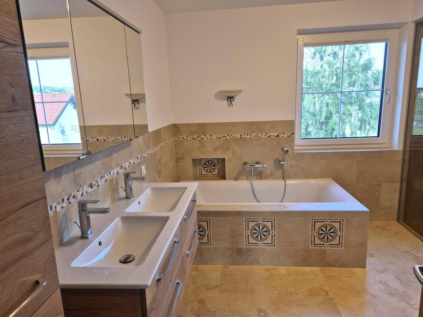 Modernes Badezimmer mit Doppelwaschbecken, Badewanne und beigen Fliesen.