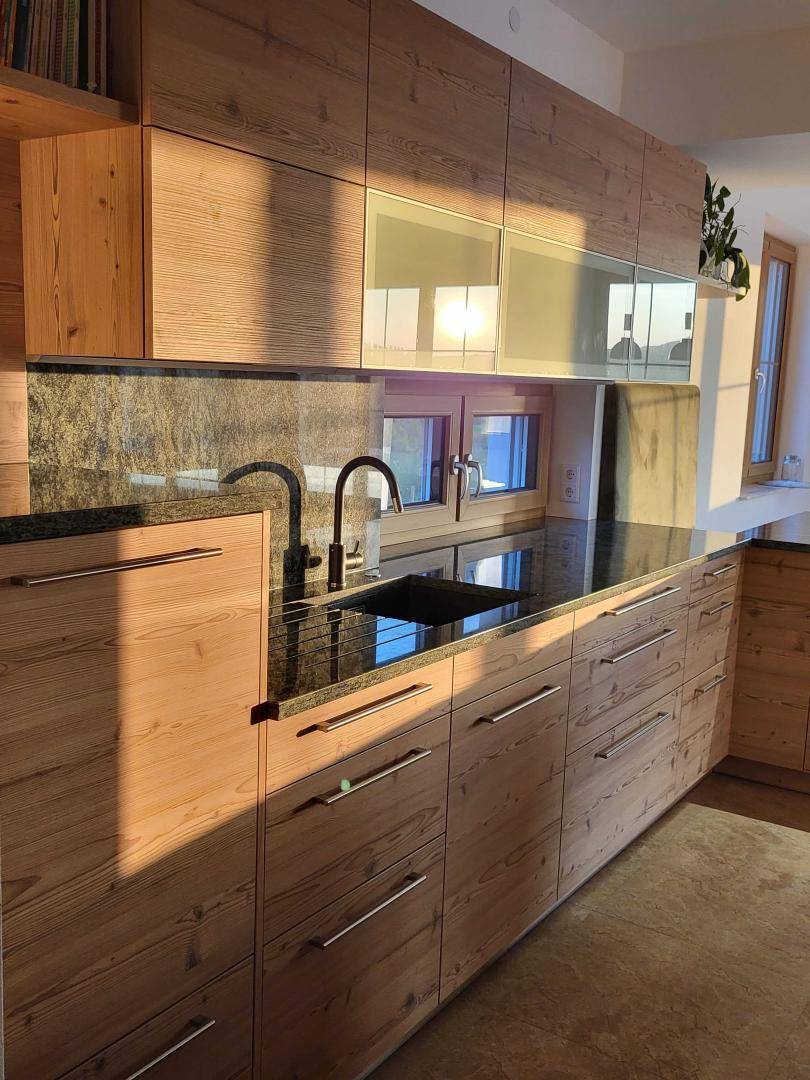 Moderne Holzküche mit dunkler Granitarbeitsplatte und viel natürlichem Licht.