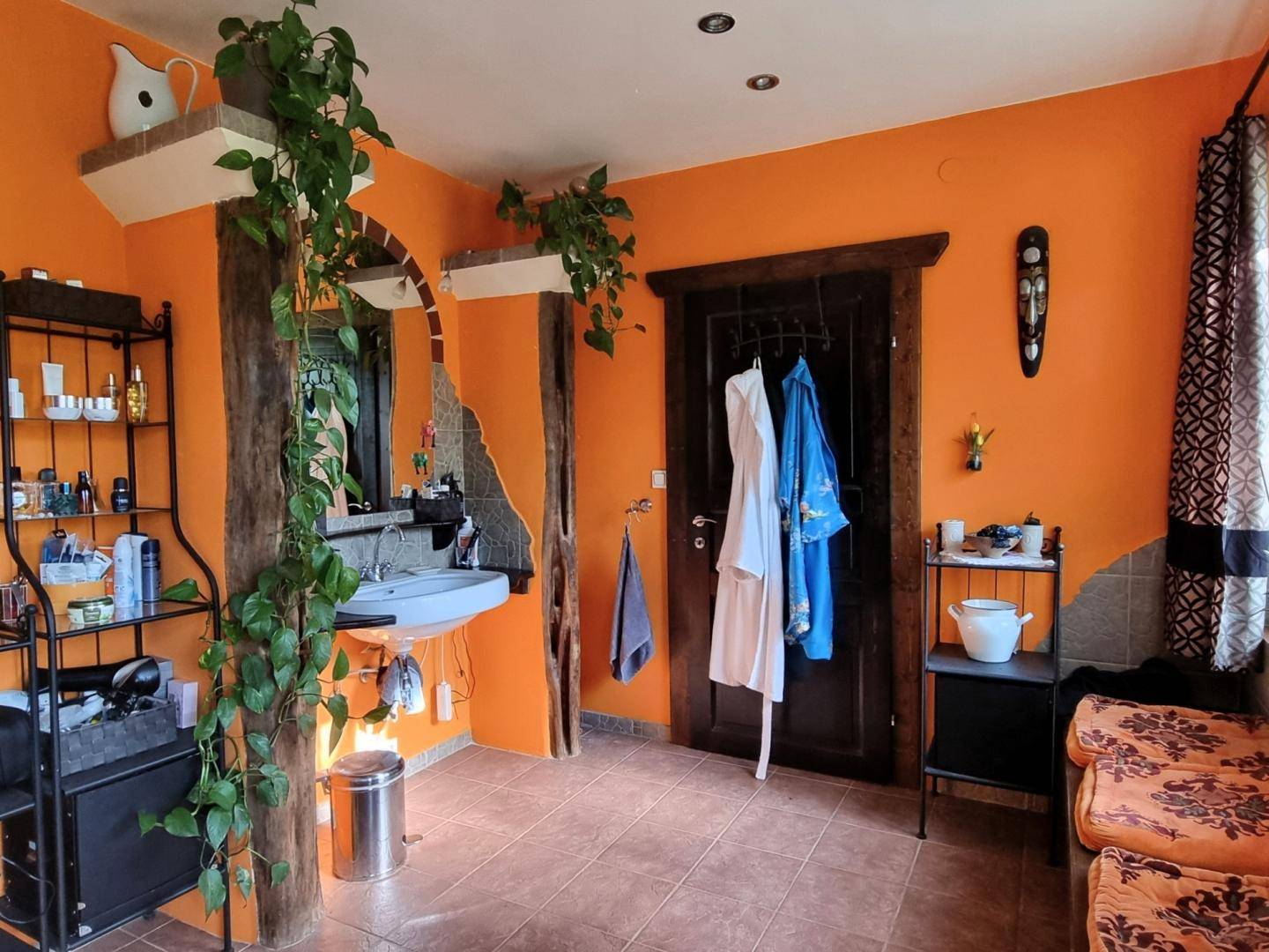 Badezimmer mit orangefarbenen Wänden, Waschbecken und rustikalen Holzelementen, individuell eingerichtet.