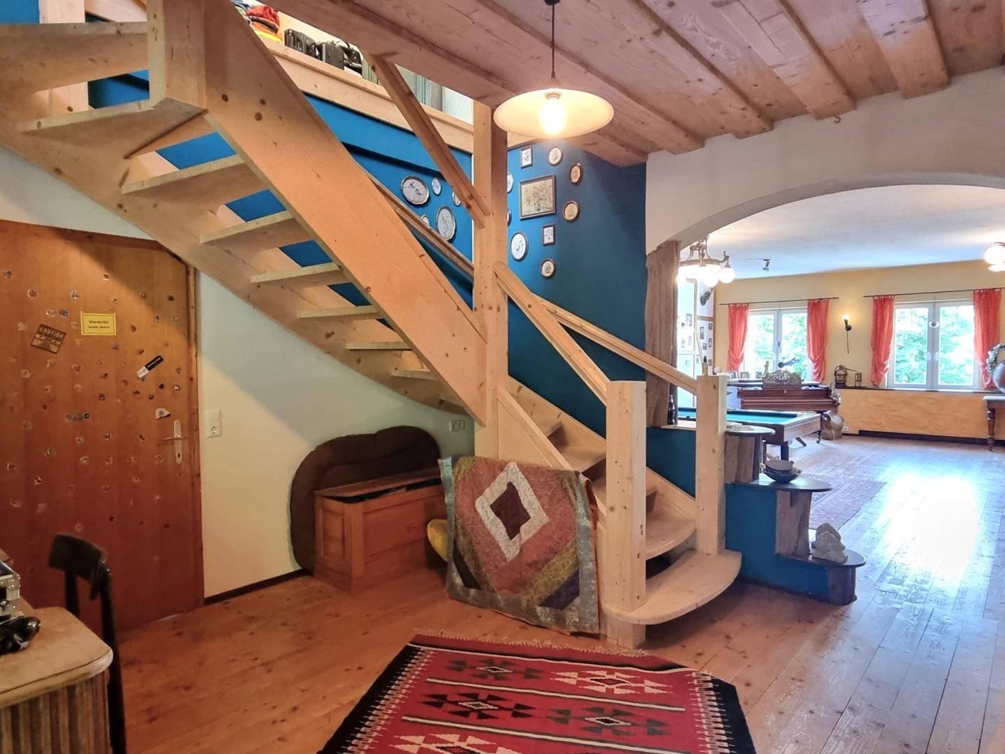 Heller Flur mit Holztreppe und Holzboden, der zu den oberen Etagen und dem Wohnbereich führt.