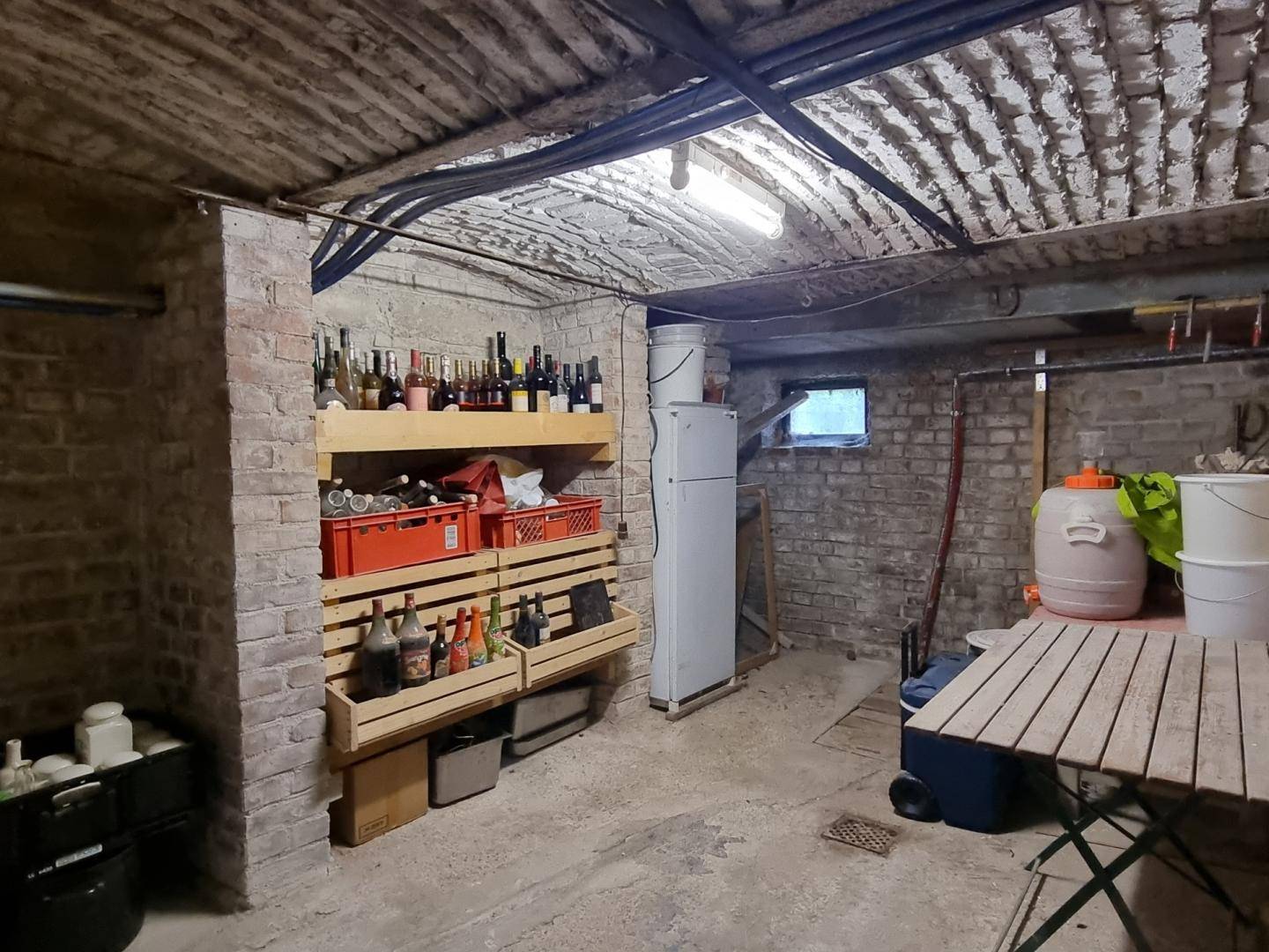 Rustikaler Kellerraum mit Ziegelwänden, Weinregalen und Stauraum für Vorräte.