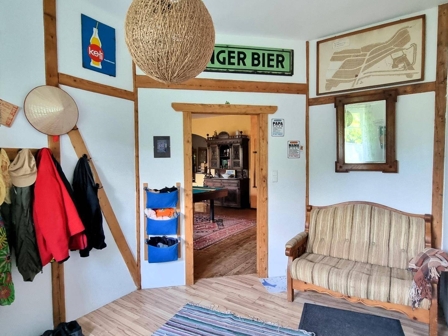 Gemütlicher Eingangsbereich mit Holzbalken, Garderobe und kleiner Sitzbank, rustikal eingerichtet.
