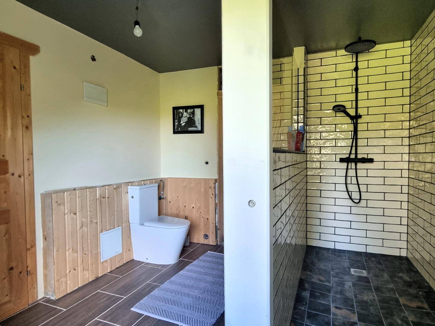 Modernes Badezimmer mit Holzakzenten, begehbarer Dusche und funktionalem WC-Bereich.