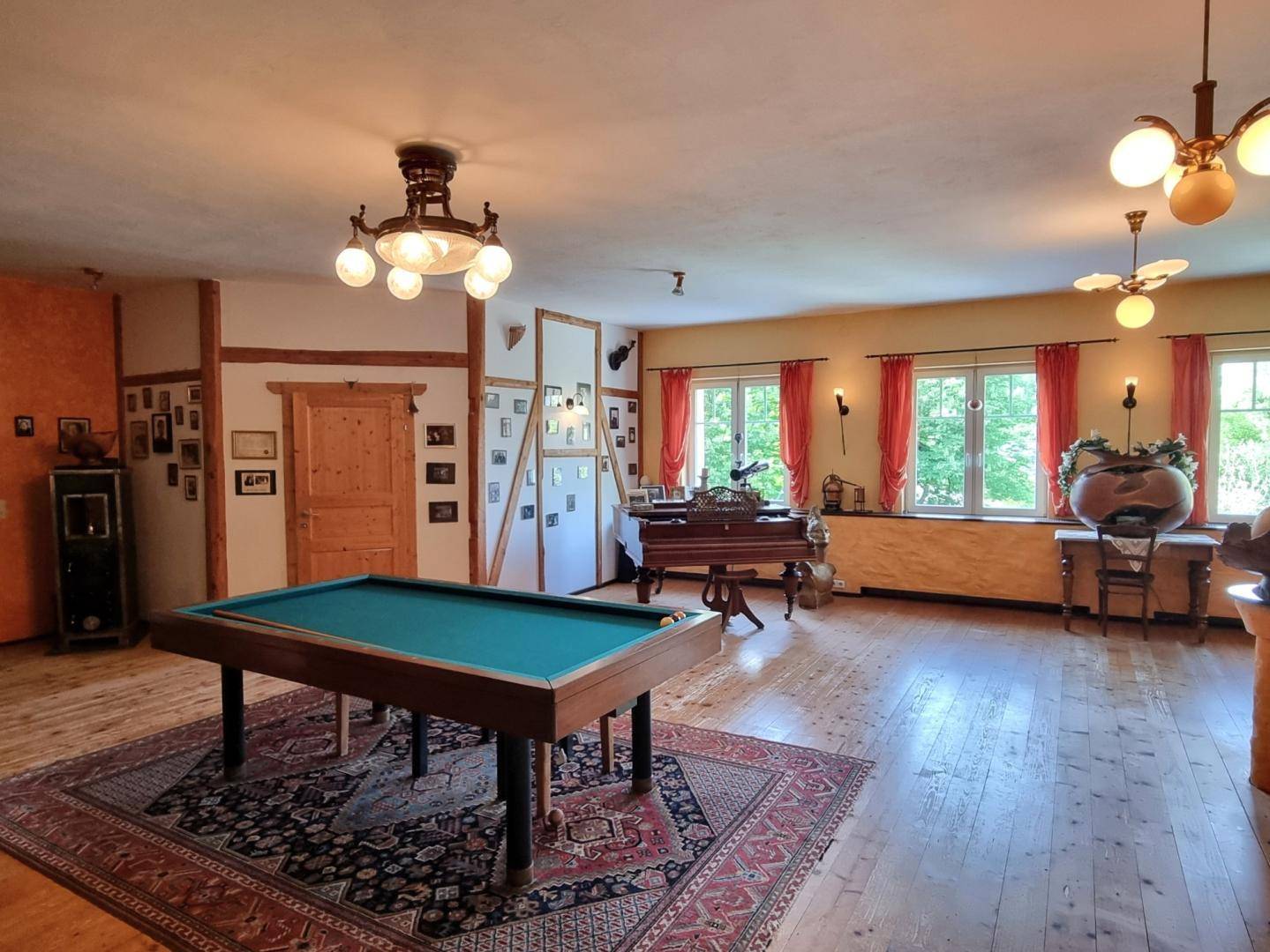 Geräumiger Wohnbereich mit Billardtisch, Holzboden und mehreren Fenstern, traditionell eingerichtet.