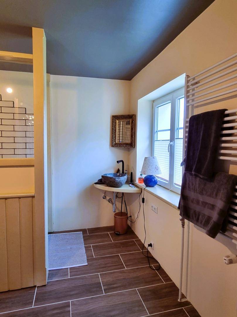 Modernes Badezimmer mit Holzbodenfliesen, Waschbecken und beheiztem Handtuchhalter, hell und funktional.