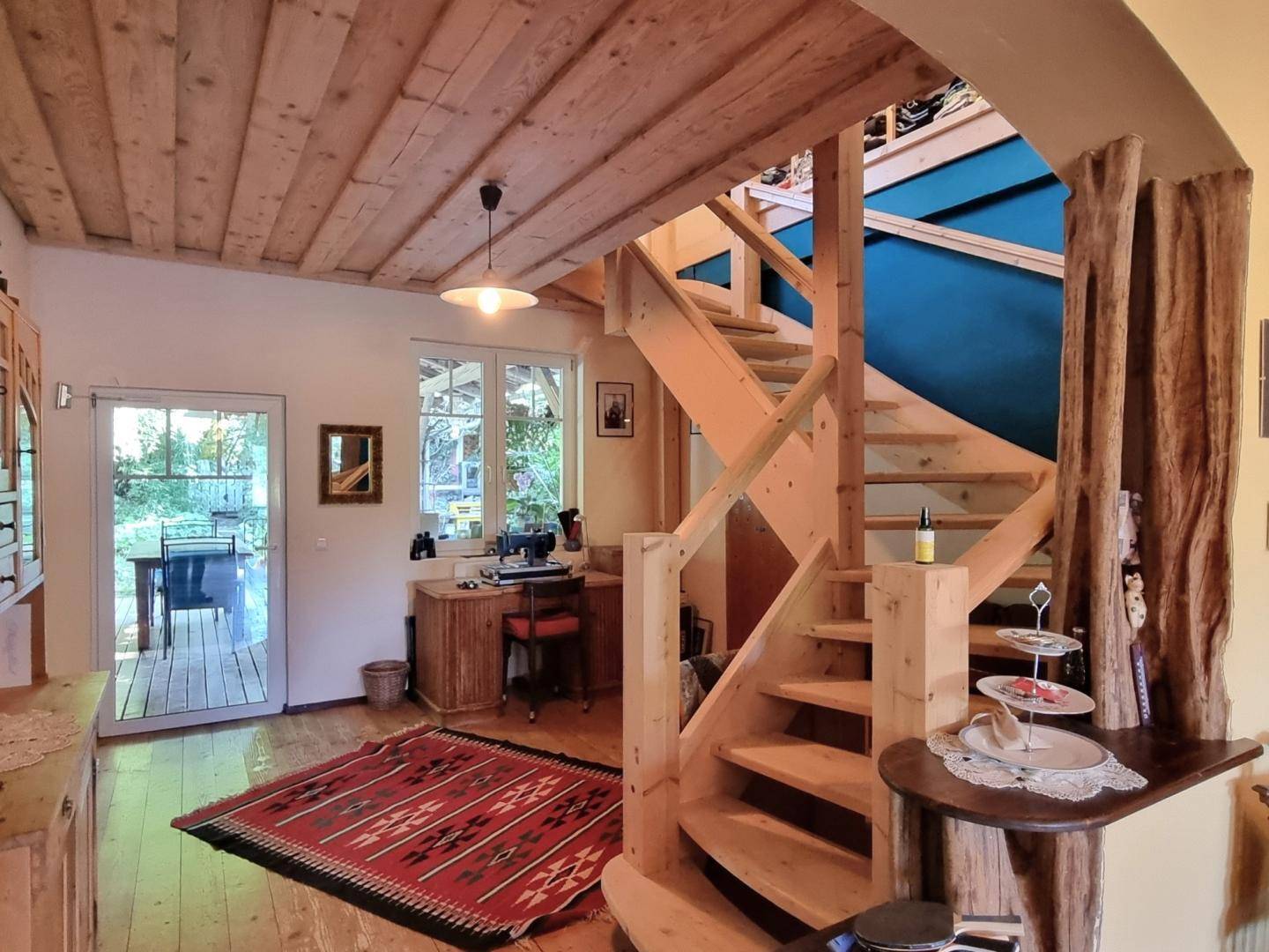 Offener Flur mit Holztreppe, Holzboden und Zugang zu einem Arbeitsbereich und dem Garten.