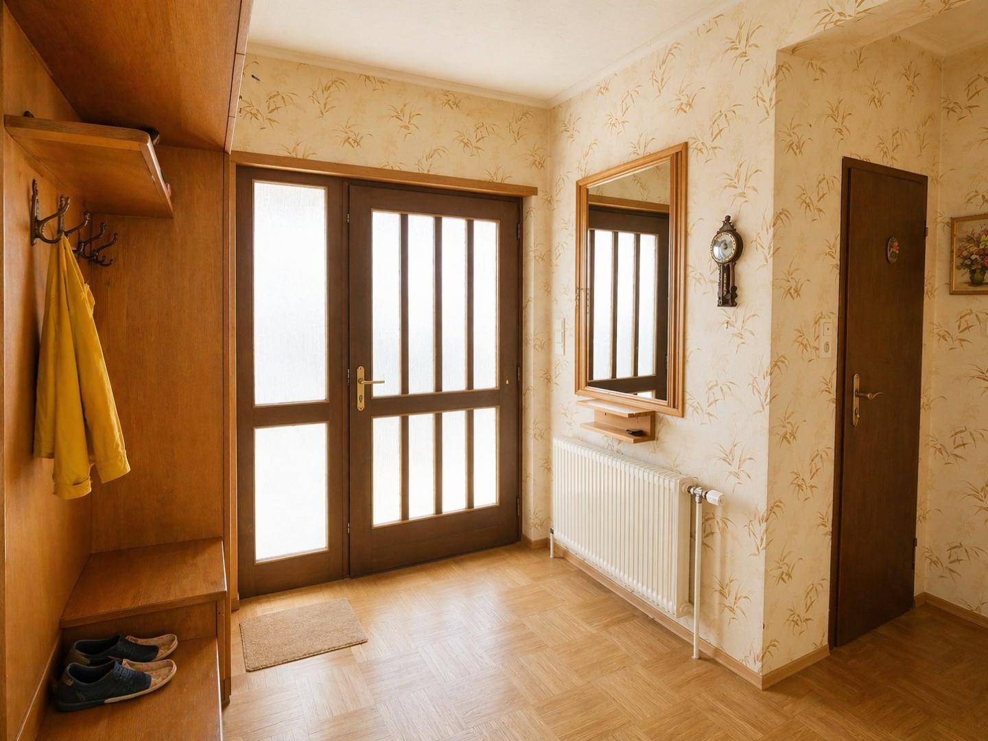 Eingangsbereich mit Garderobe, Spiegel und gemusterter Tapete, hell und einladend.
