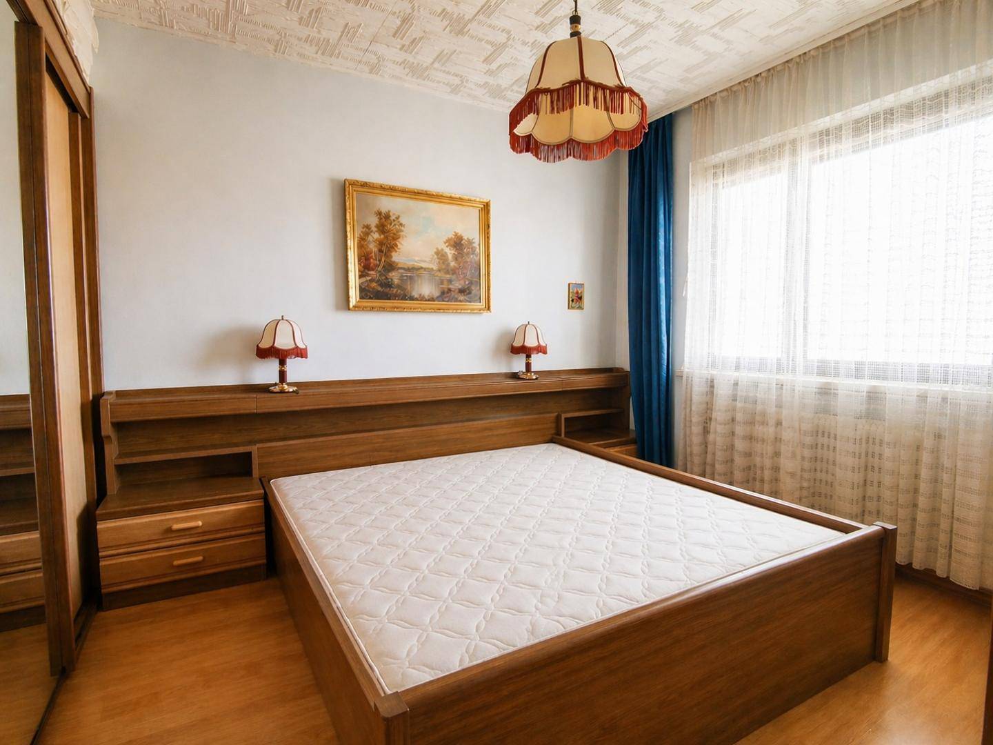Schlafzimmer mit Doppelbett, Holzrahmen und großem Fenster für viel Tageslicht.