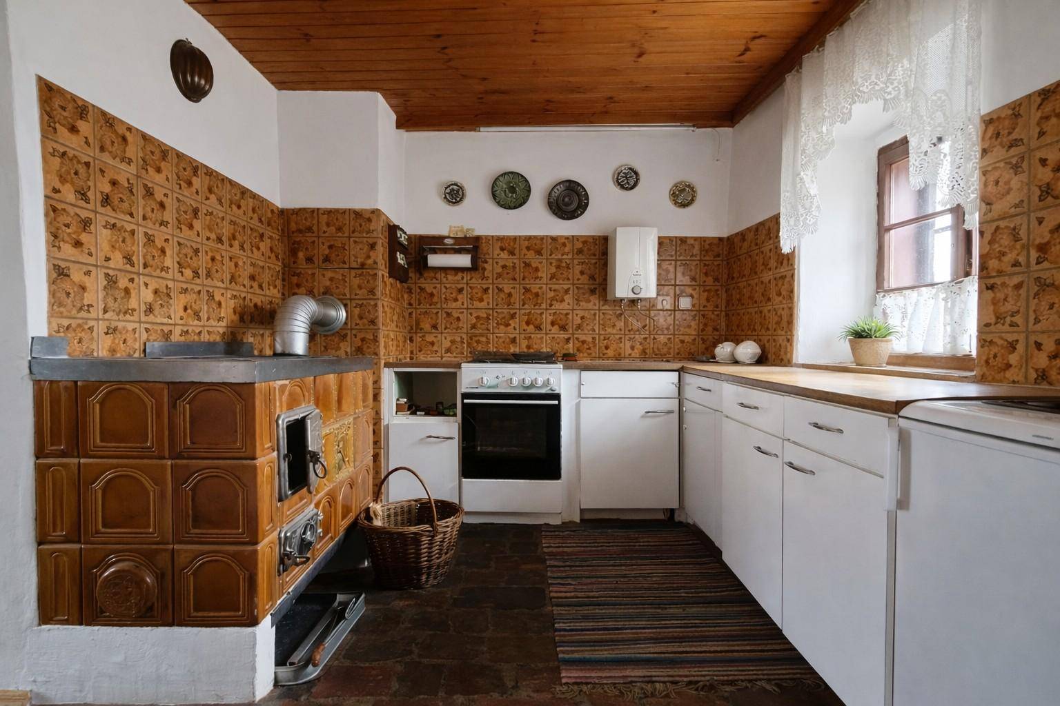 Traditionelle Küche mit Kachelofen, weißen Schränken und rustikalen Fliesen an der Wand.