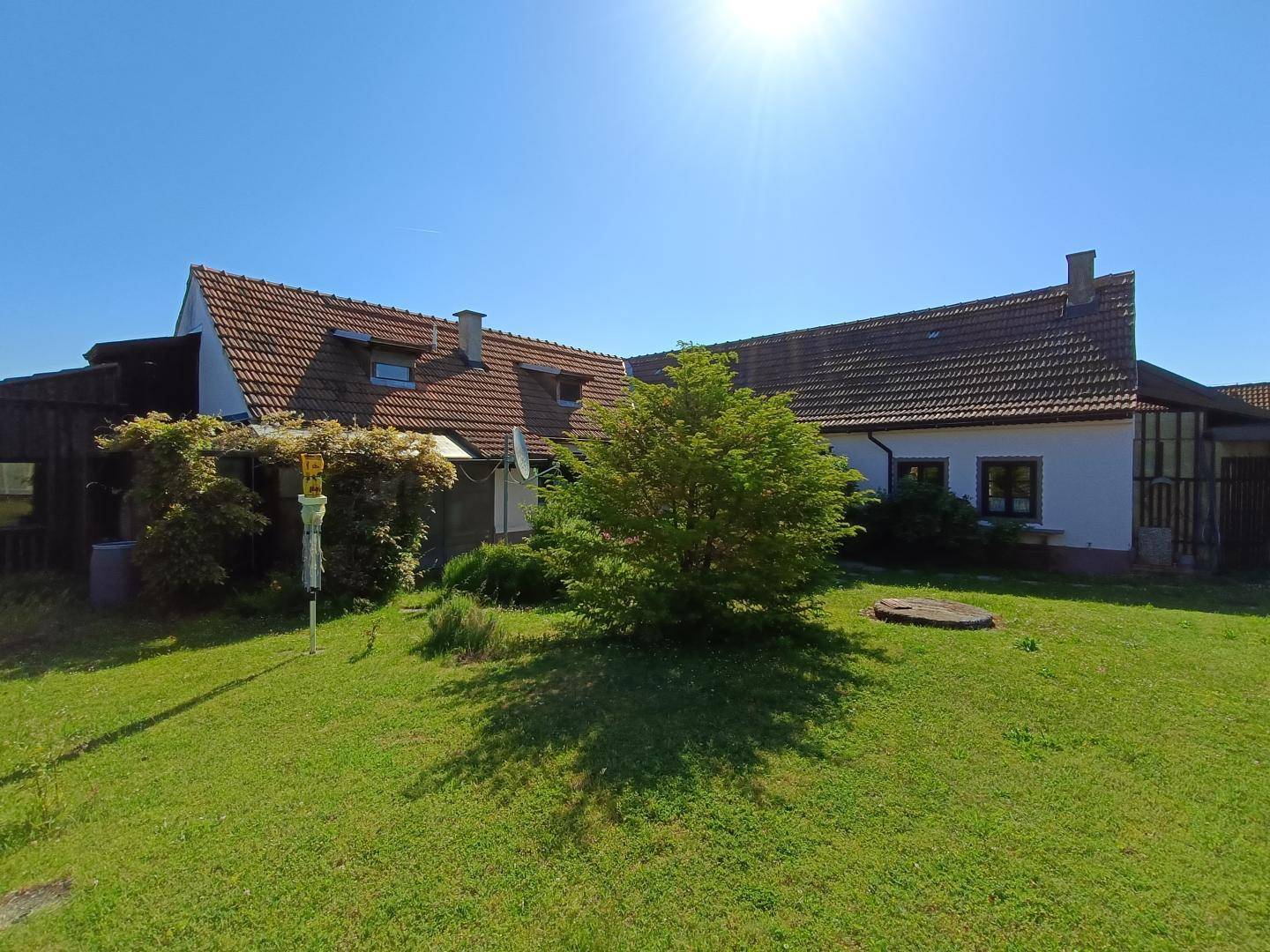 Weitläufiger Gartenbereich mit Rasenfläche und einem Baum vor dem traditionellen Landhaus.