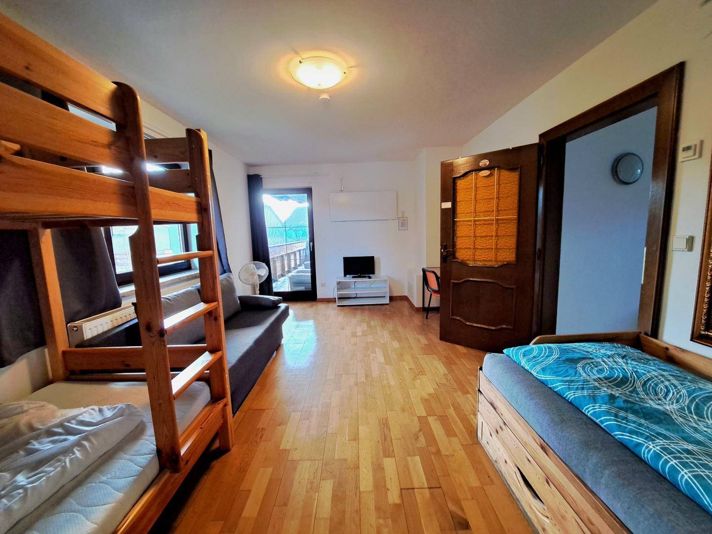 Geräumiges Schlafzimmer mit Etagenbett, Schlafsofa und Balkonzugang, ideal für mehrere Personen.