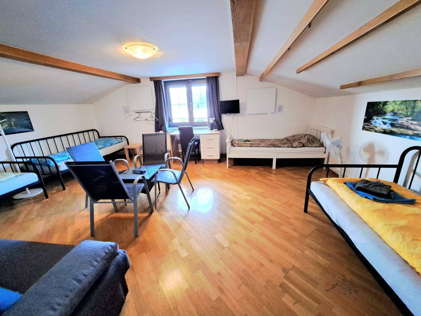 Großes Dachgeschosszimmer mit mehreren Betten, Holzbalken und viel Platz, ideal für Gruppen.