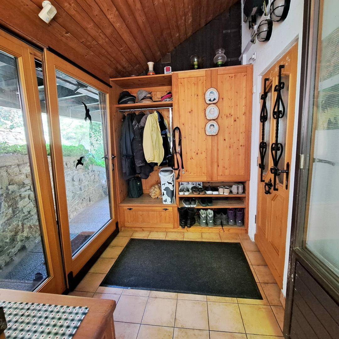 Eingangsbereich mit Holzverkleidung, Fliesenboden und praktischen Garderobenschränken.