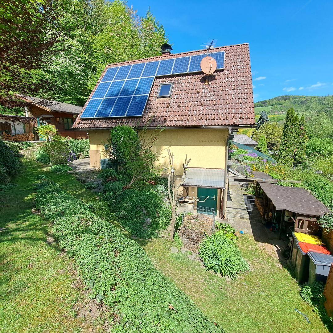Rückseite des Hauses mit Photovoltaikanlage auf dem Dach und großem Gartenbereich.