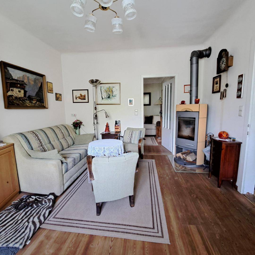 Helles Wohnzimmer mit Holzboden, modernem Kaminofen und bequemen Sitzmöbeln.